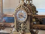 une horloge en or posée sur une table devant un miroir