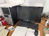 a desk with a computer, keyboard, mouse, and other items on it