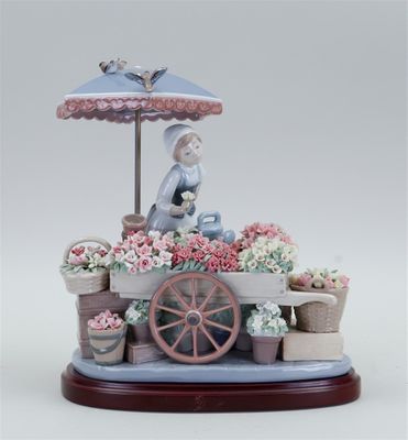 une figurine représentant une femme assise devant un étal de fleurs