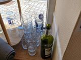 bottles and glasses on a shelf in front of a window with a sign on it
