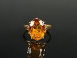 une bague sertie d'un saphir orange sur un fond noir