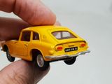 someone is holding a toy car in their hand on a white surface