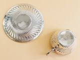 a silver plate and a silver candle holder on a yellow surface