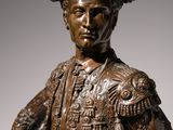bronze statue of a man with a hat and gloves holding a sword
