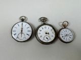 three different types of pocket watches sitting on a white surface