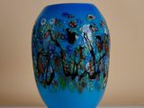 a blue vase sitting on a table with flowers on it