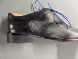 grey leather shoes with blue laces hang on a wall