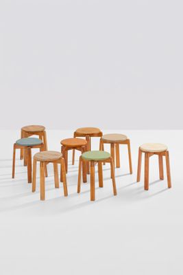 several wooden stools with different colored cushions in a white room
