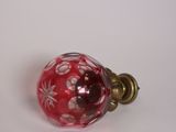 une boule en verre rouge ornée de fleurs blanches