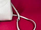 the white purse is sitting on a red surface with a strap