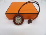 an orange box with a brown strap around it and a clock on top of it
