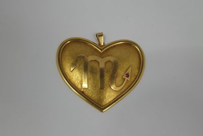 a gold heart shaped locke with the letter m on it