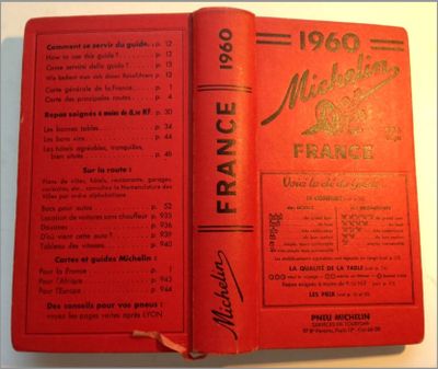 an old book with a red cover sitting on top of a table