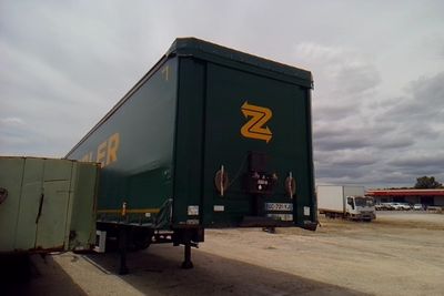 un grand camion vert garé devant un immeuble
