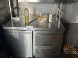 une petite cuisine avec un plan de travail en inox et un réfrigérateur