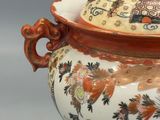 a large orange and white vase with a lid on a table