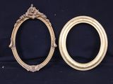two gold oval frames with ornate designs on a black background