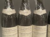 six bottles of wine wrapped in plastic sit on a shelf