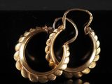 une paire de boucles d'oreilles en or sur une surface noire