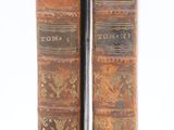 two old books sitting on top of each other on a white surface