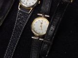 two watches sitting next to each other on a black bag