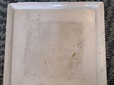 a dirty plate on the floor with a small amount of dirt on it