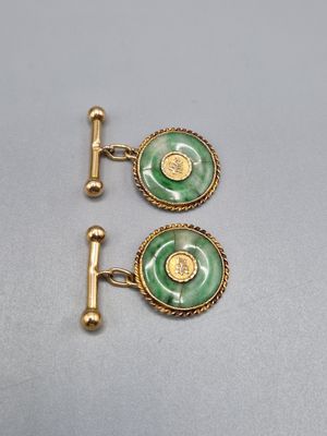 a pair of green and gold cufflinks on a white surface