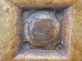 a rusted metal square with a hole in the middle