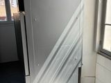 sunlight shines through a window onto a white refrigerator in a room