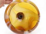 someone is holding a yellow glass vase with a hole in it
