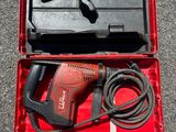 an electric drill in a red case on the ground