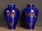 two blue vases with gold designs on them sitting on a table
