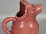 a brown pitcher with an open mouth sitting on a table