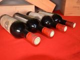 several bottles of wine are lined up on a red table cloth