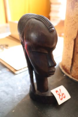 une sculpture en bois représentant la tête d'une femme, posée sur une table