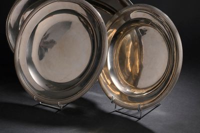 deux assiettes en argent posées sur un support, sur une surface noire