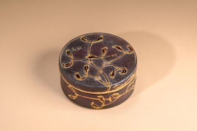 a small round box with a decorative design on it