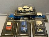 five toy cars in a display case on a table