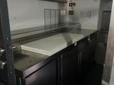 une cuisine avec des placards en inox et un plan de travail blanc