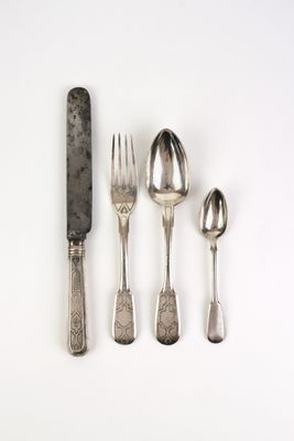 cinq cuillères en argent et un couteau posés sur un plan de travail blanc