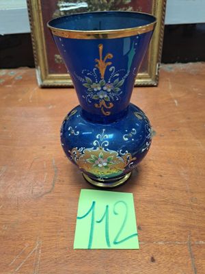 un vase bleu posé sur une table en bois à côté d'un cadre photo