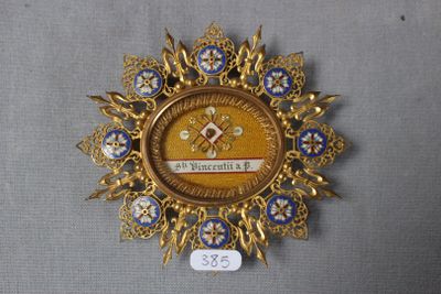 une image représentant une broche dorée et bleue posée sur une surface grise