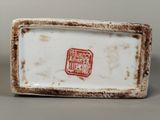 a small white plate with a red stamp on it