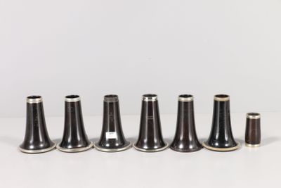 six vases noirs et blancs sont alignés sur une surface blanche