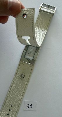 a hand that is holding a watch on a white surface