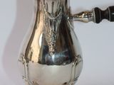 a silver coffee pot with a wooden handle on a white surface