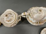 two white and gold teapots and saucers on a table