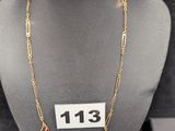 collier à chaîne en or orné de pierres rouges, exposé dans une vitrine