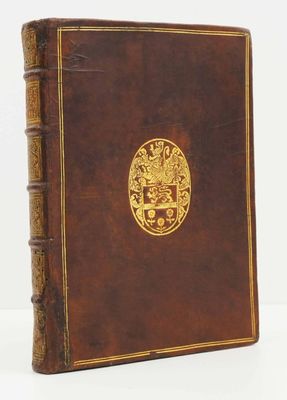 un vieux livre brun portant un emblème doré