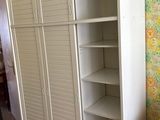 a white cabinet in the corner of a room with a wallpapered wall